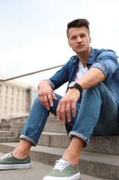 Photo of Portrait of handsome young man sitting on stairs outdoors