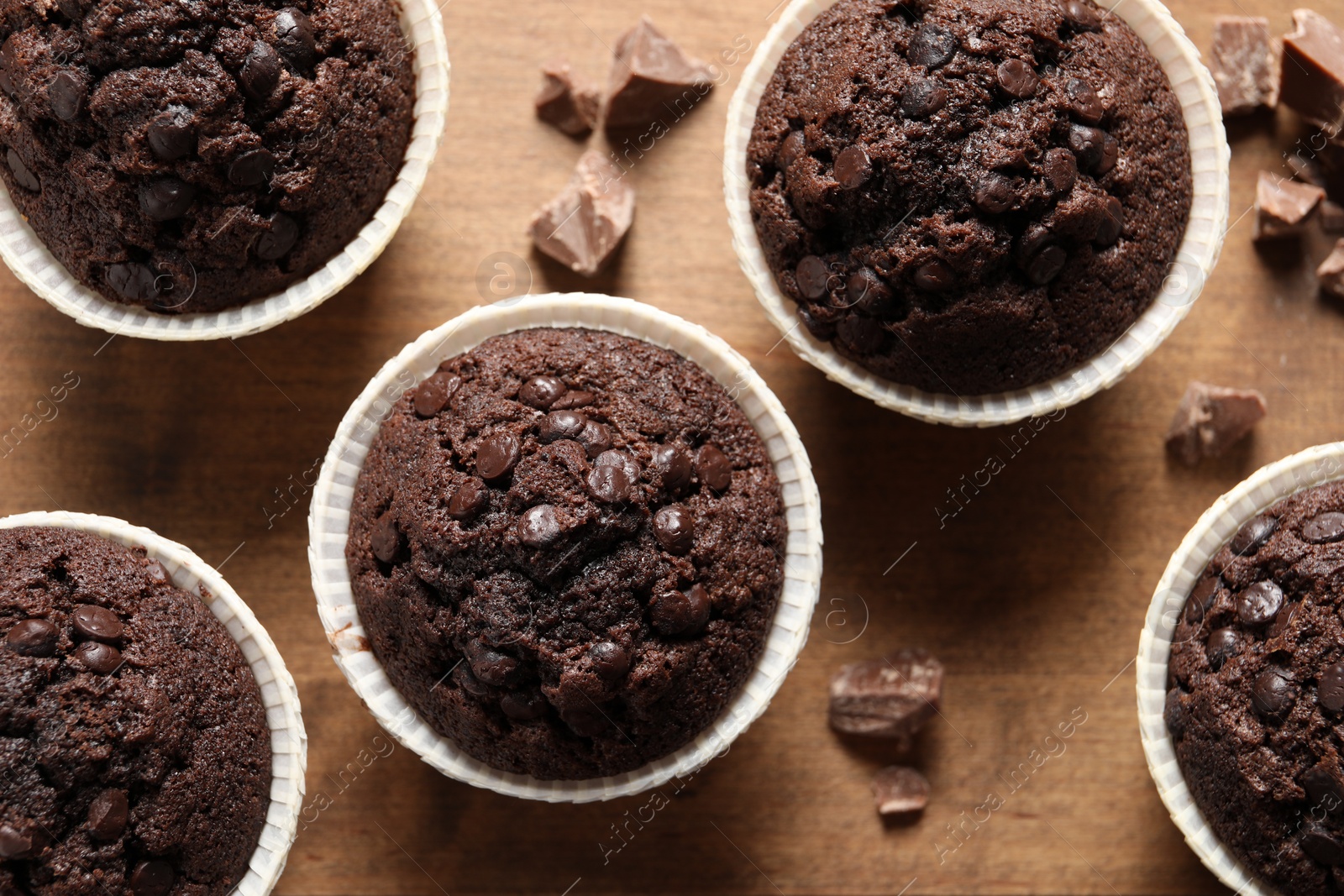 Photo of Delicious chocolate muffins on wooden table, flat lay
