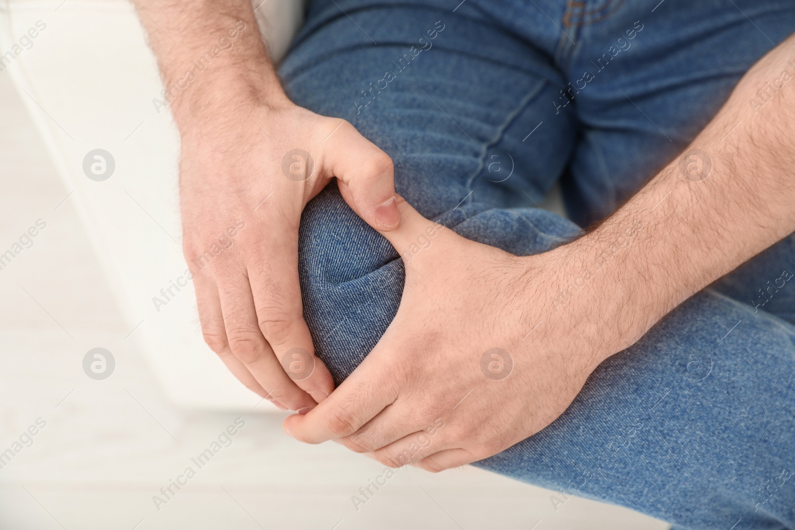 Photo of Young man suffering from leg pain indoors, closeup