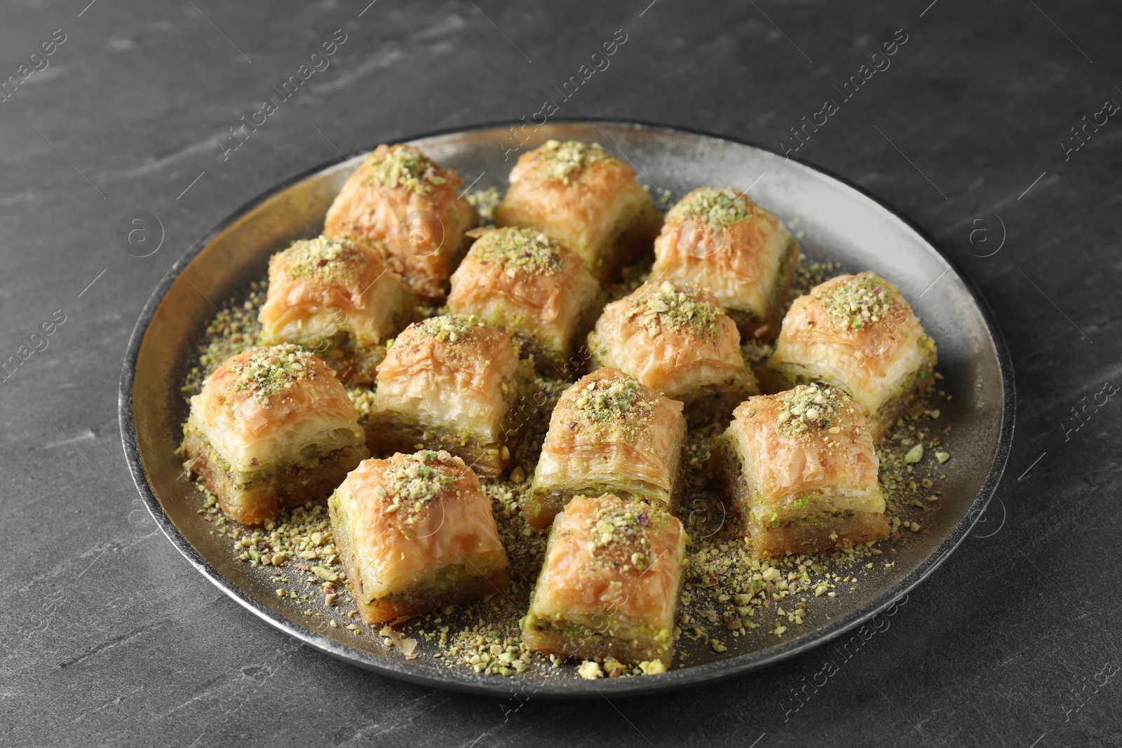 Photo of Delicious fresh baklava with chopped nuts on grey table. Eastern sweets