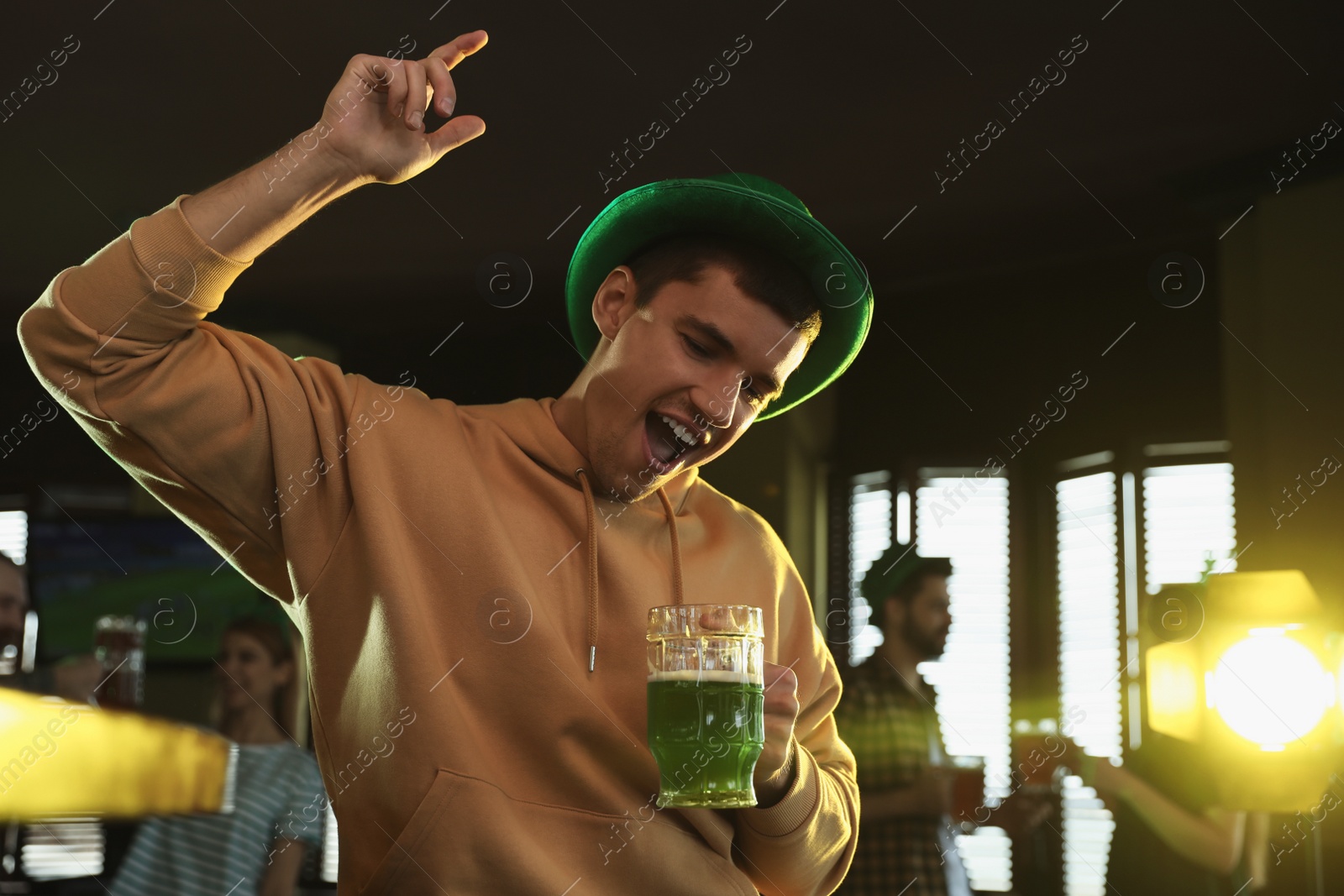 Photo of Emotional man with glass of green beer in pub. St. Patrick's Day celebration