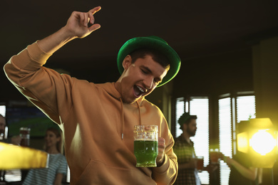 Photo of Emotional man with glass of green beer in pub. St. Patrick's Day celebration