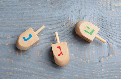 Photo of Hanukkah traditional dreidels with letters Nun, He and Gimel on grey wooden table, flat lay