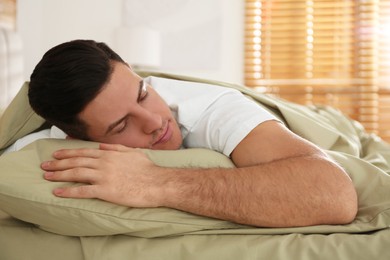 Man sleeping in bed with green linens at home