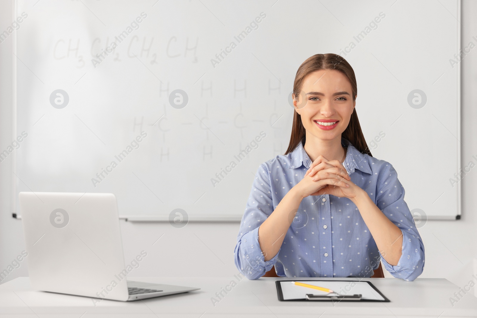 Photo of Young chemistry teacher at table in classroom. Space for text