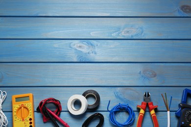 Photo of Wires and electrician's tools on light blue wooden table, flat lay. Space for text
