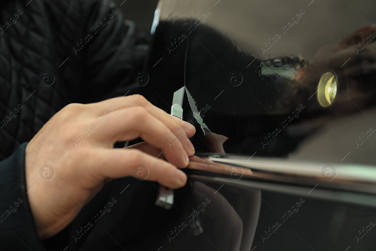 Photo of Man tinting car window with foil, closeup