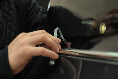 Photo of Man tinting car window with foil, closeup