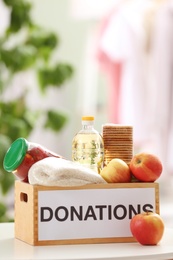 Photo of Donation box with food products on table indoors