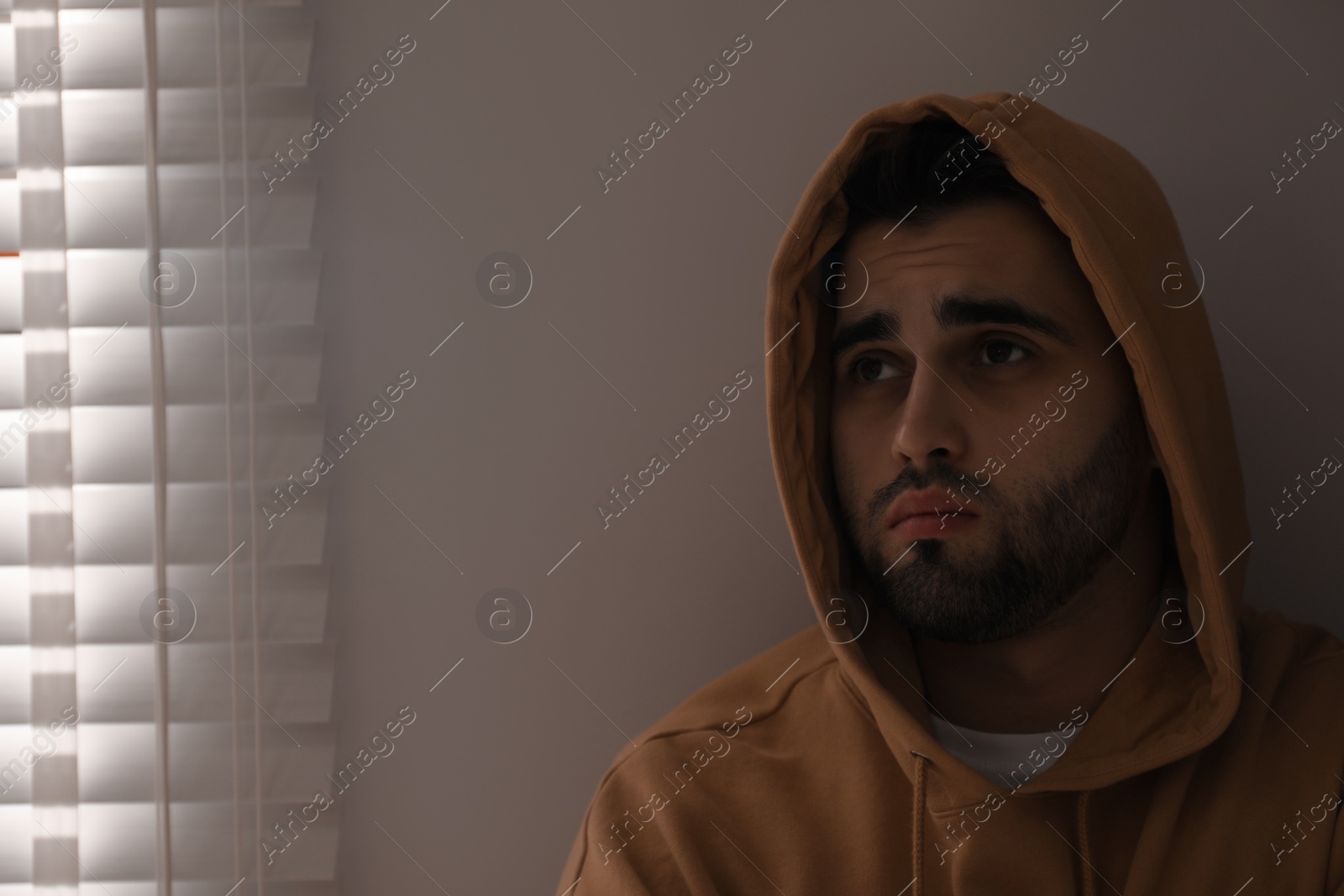 Photo of Sad young man at home. Space for text