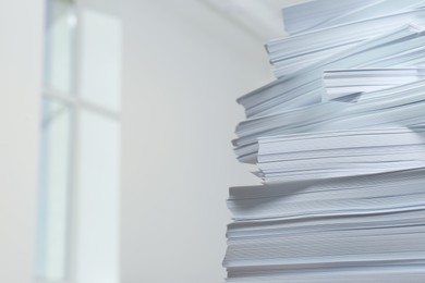 Stack of paper sheets against blurred background, closeup. Space for text