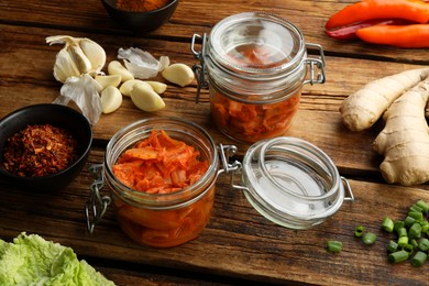 Photo of Delicious kimchi with Chinese cabbage and ingredients on wooden table