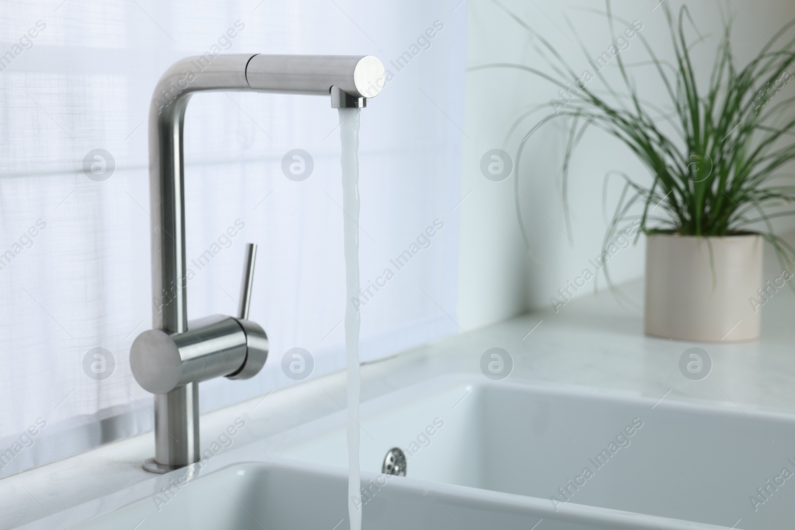 Photo of Stream of water flowing from tap in kitchen