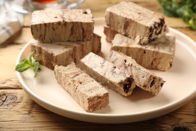 Photo of Tasty chocolate halva with mint on wooden table, closeup