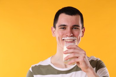 Photo of Milk mustache left after dairy product. Man drinking milk on orange background, space for text