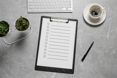 Photo of Clipboard with checkboxes, cup of coffee, plants and computer keyboard on light grey table, flat lay. Checklist
