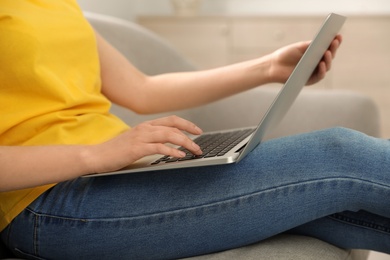 Blogger working with modern laptop on sofa at home, closeup