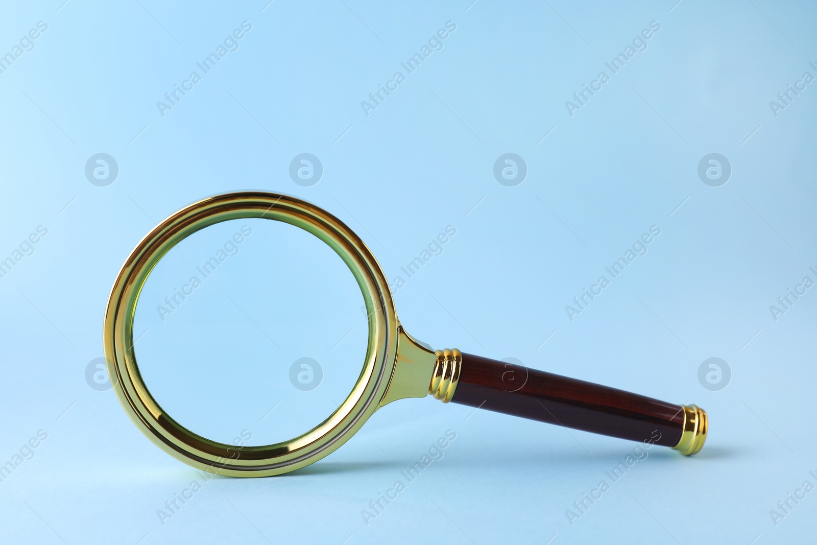 Photo of Magnifying glass with handle on light blue background