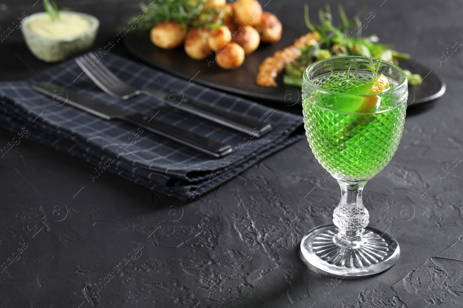 Photo of Delicious drink with tarragon in glass on dark textured table. Space for text