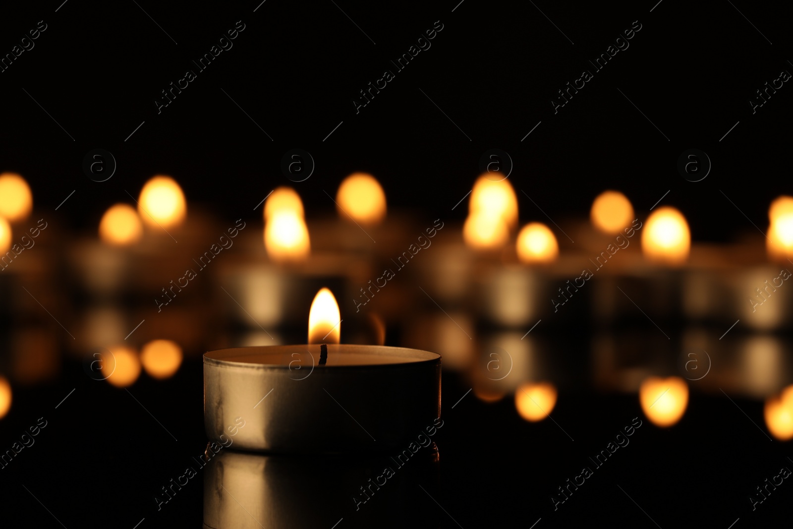 Photo of Burning candle on surface in darkness, closeup. Space for text