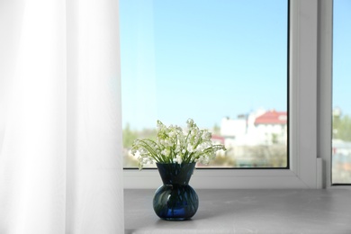 Beautiful lily of the valley bouquet in vase on windowsill