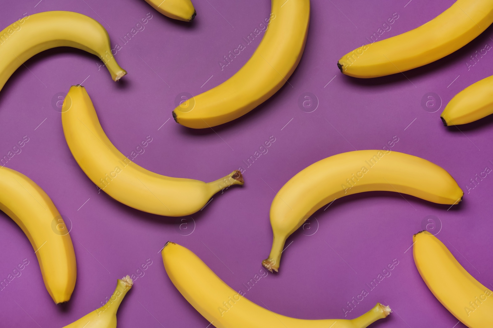 Photo of Ripe yellow bananas on purple background, flat lay