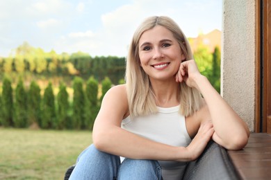Photo of Portrait of beautiful woman sitting near house in yard, space for text