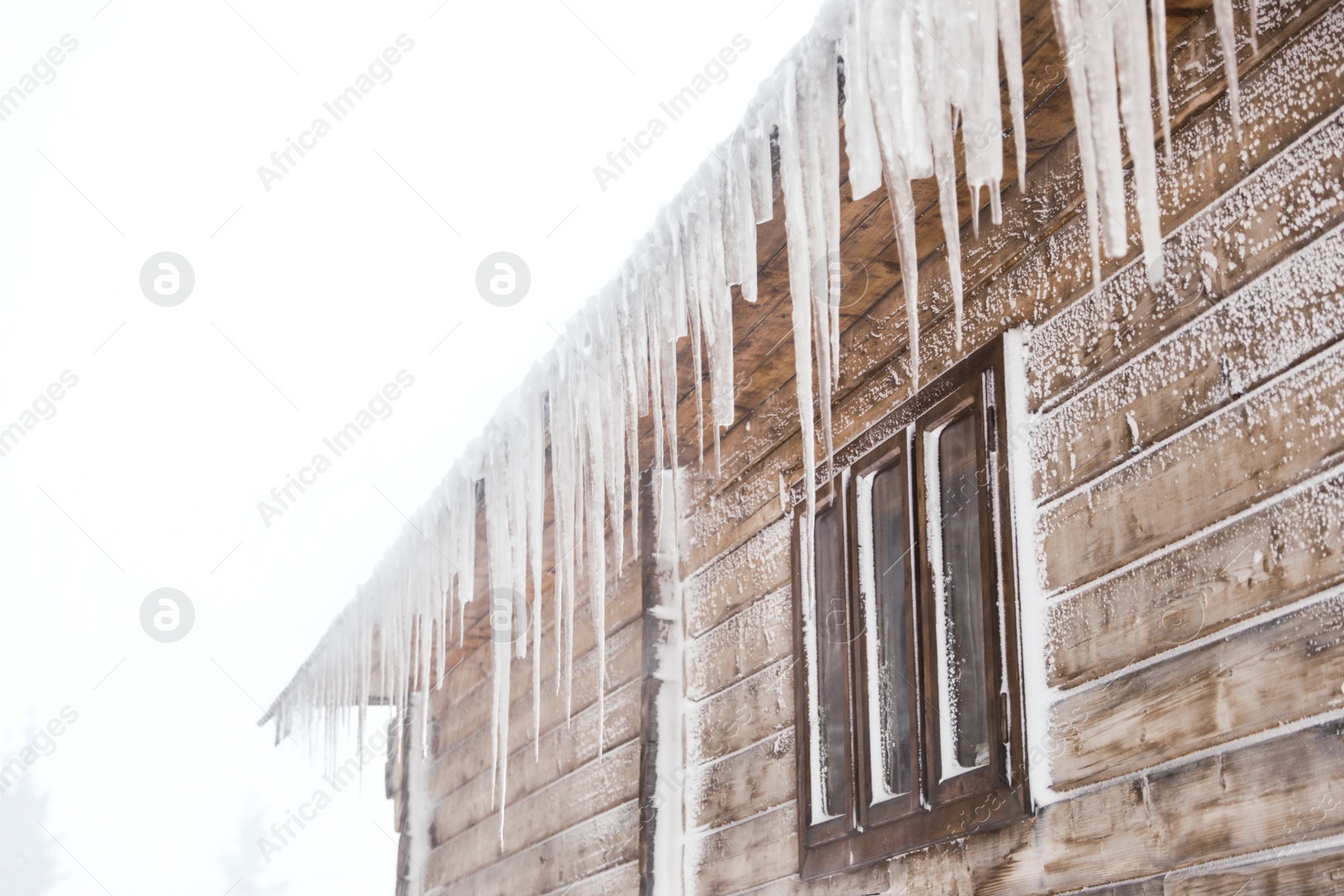 Photo of Wooden house with icicles on snowy day. Winter vacation