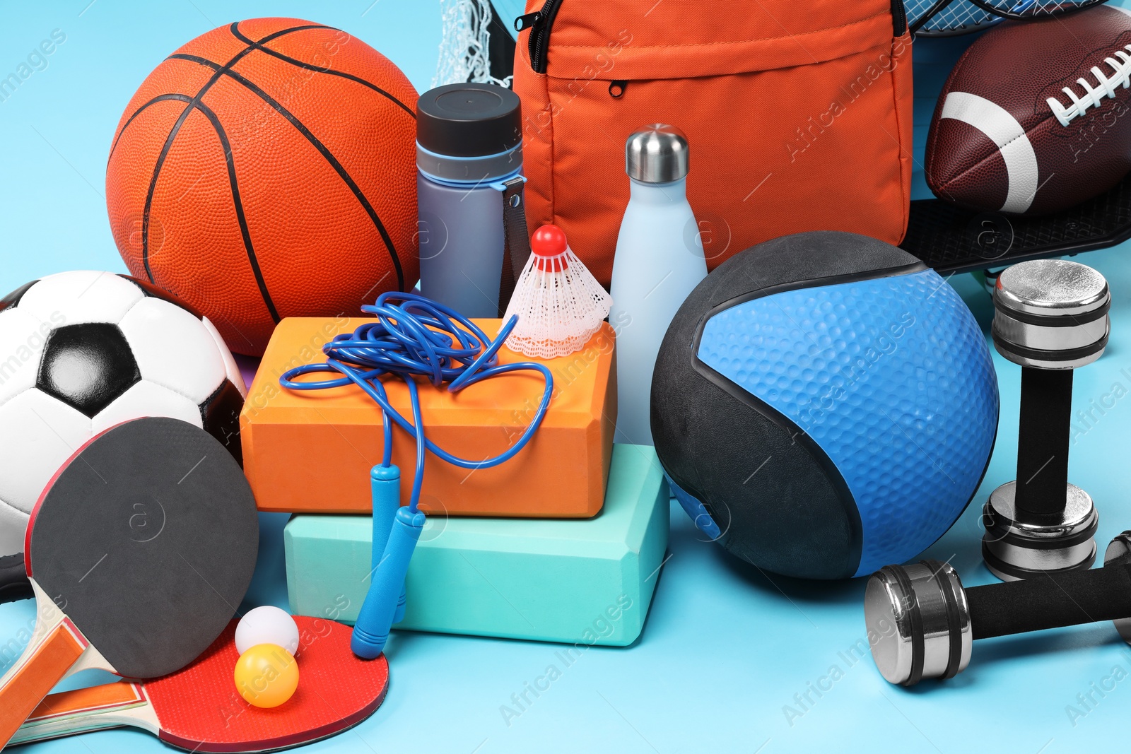 Photo of Many different sports equipment on light blue background, closeup