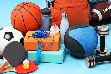 Many different sports equipment on light blue background, closeup