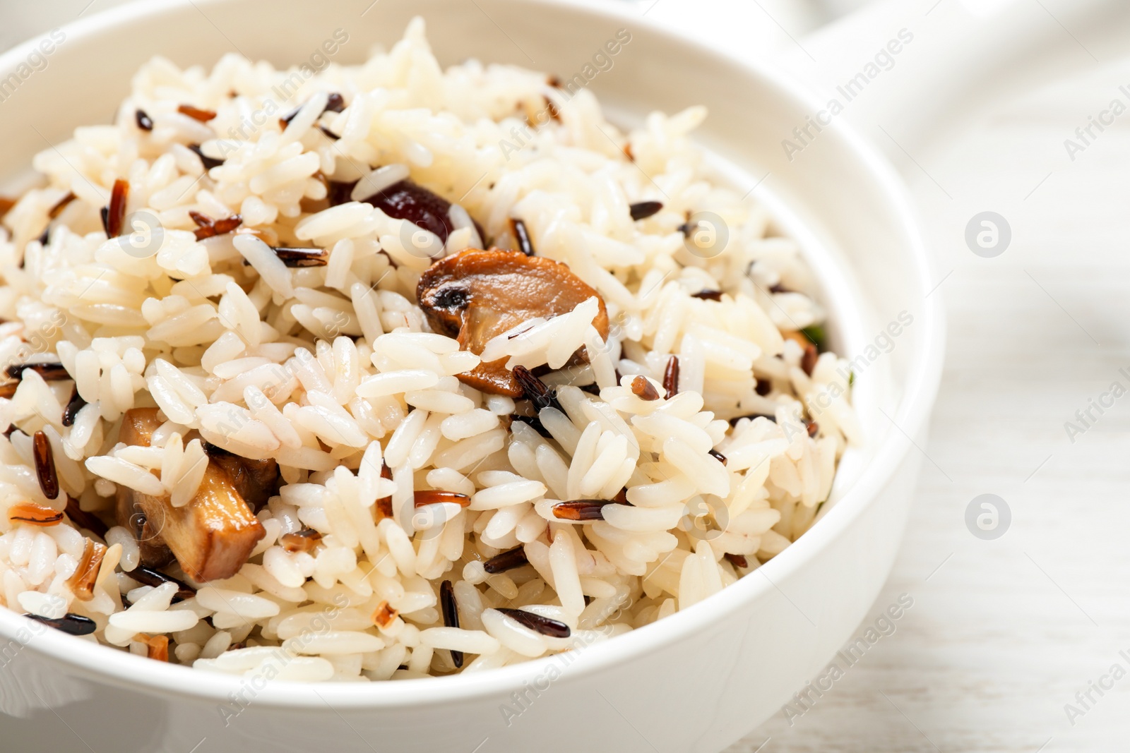 Photo of Delicious rice pilaf with mushrooms on white table, closeup