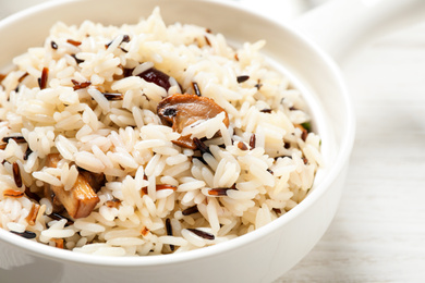 Delicious rice pilaf with mushrooms on white table, closeup