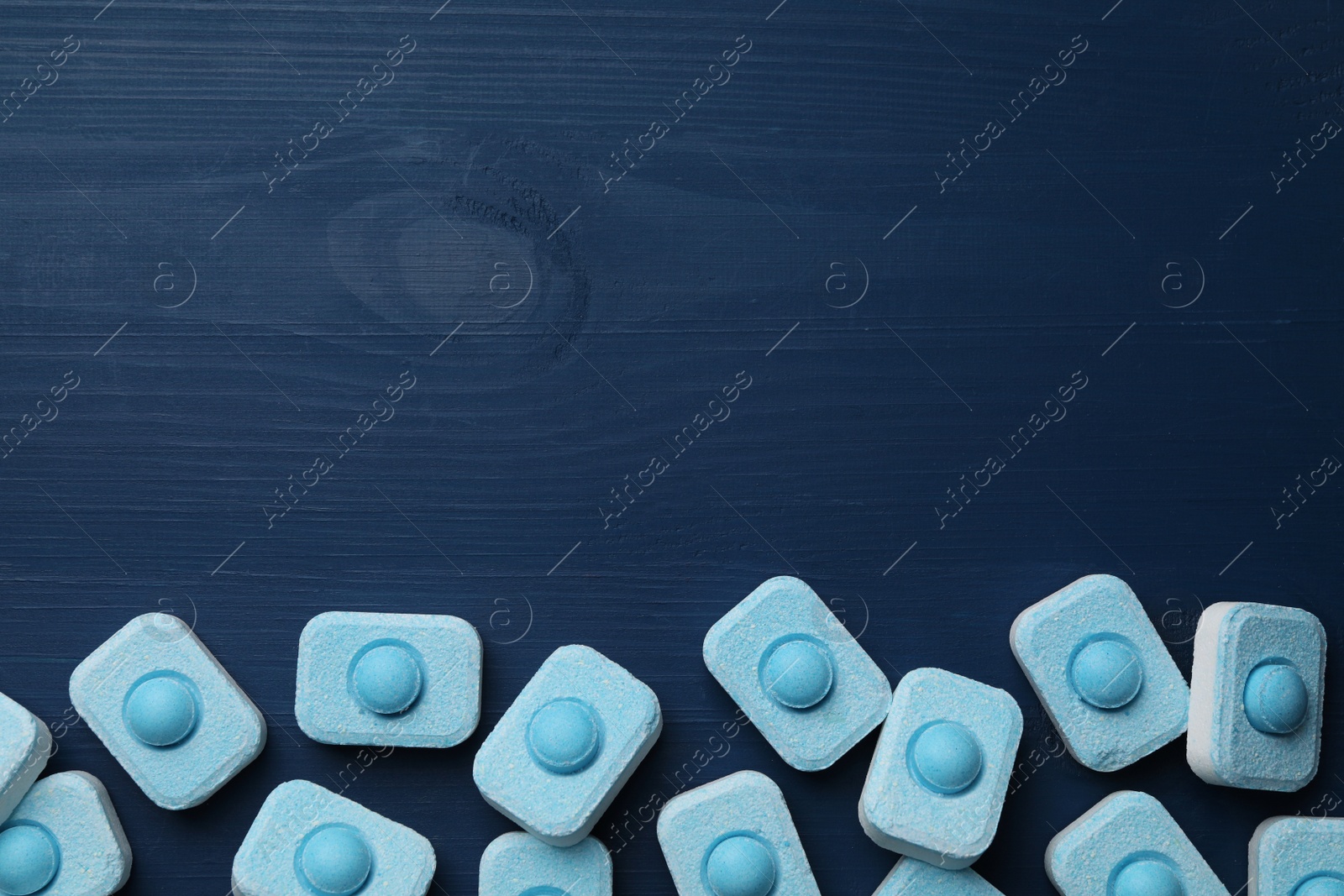 Photo of Water softener tablets on blue wooden table, flat lay. Space for text