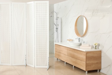 Modern bathroom interior with shower stall and folding screen