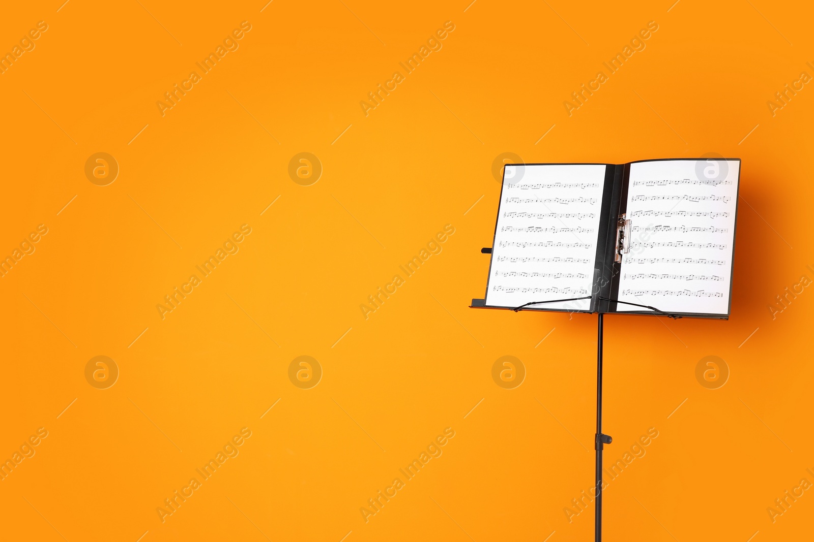 Photo of Note stand with music sheets on color background. Space for text