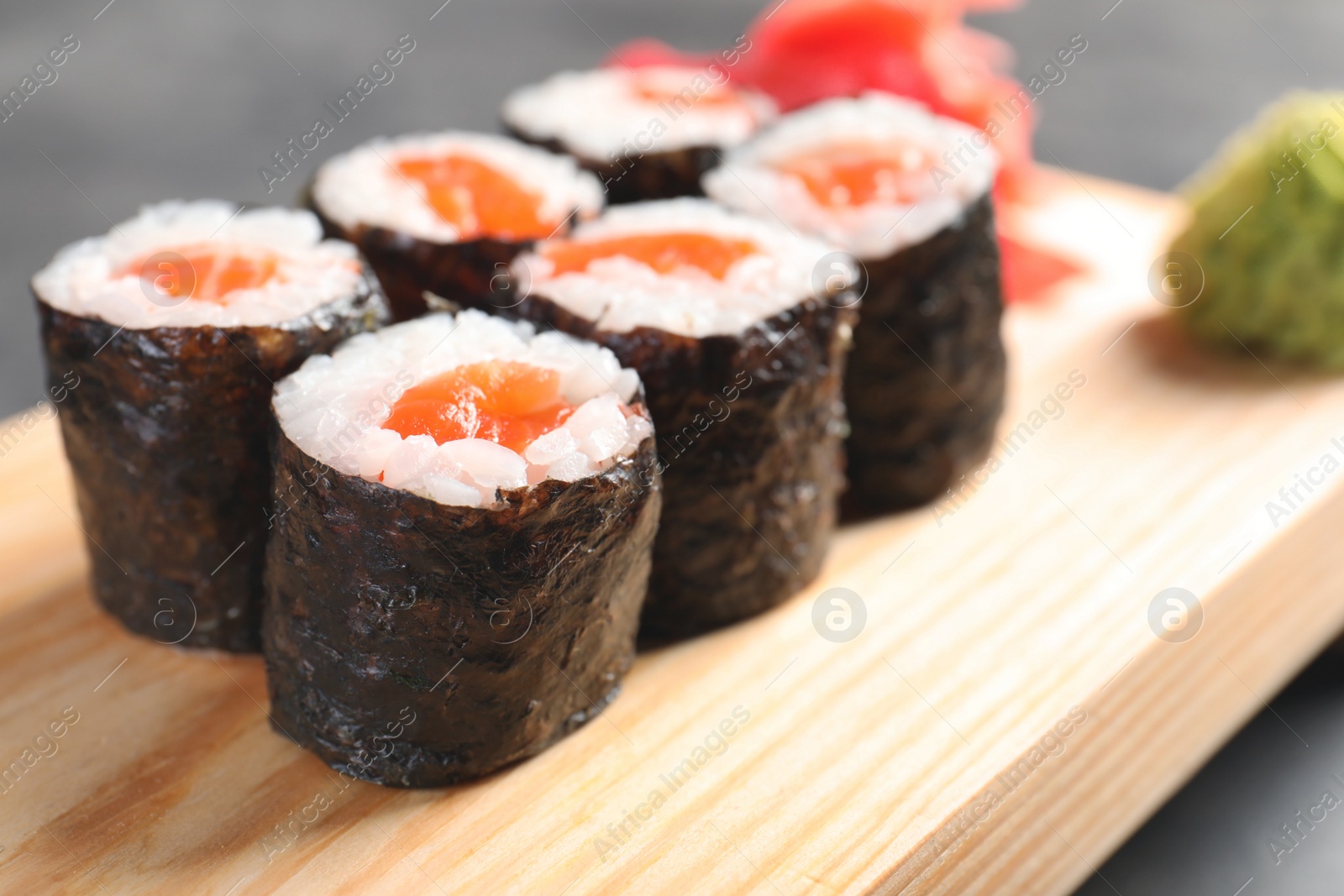 Photo of Tasty sushi rolls on wooden board, closeup. Food delivery