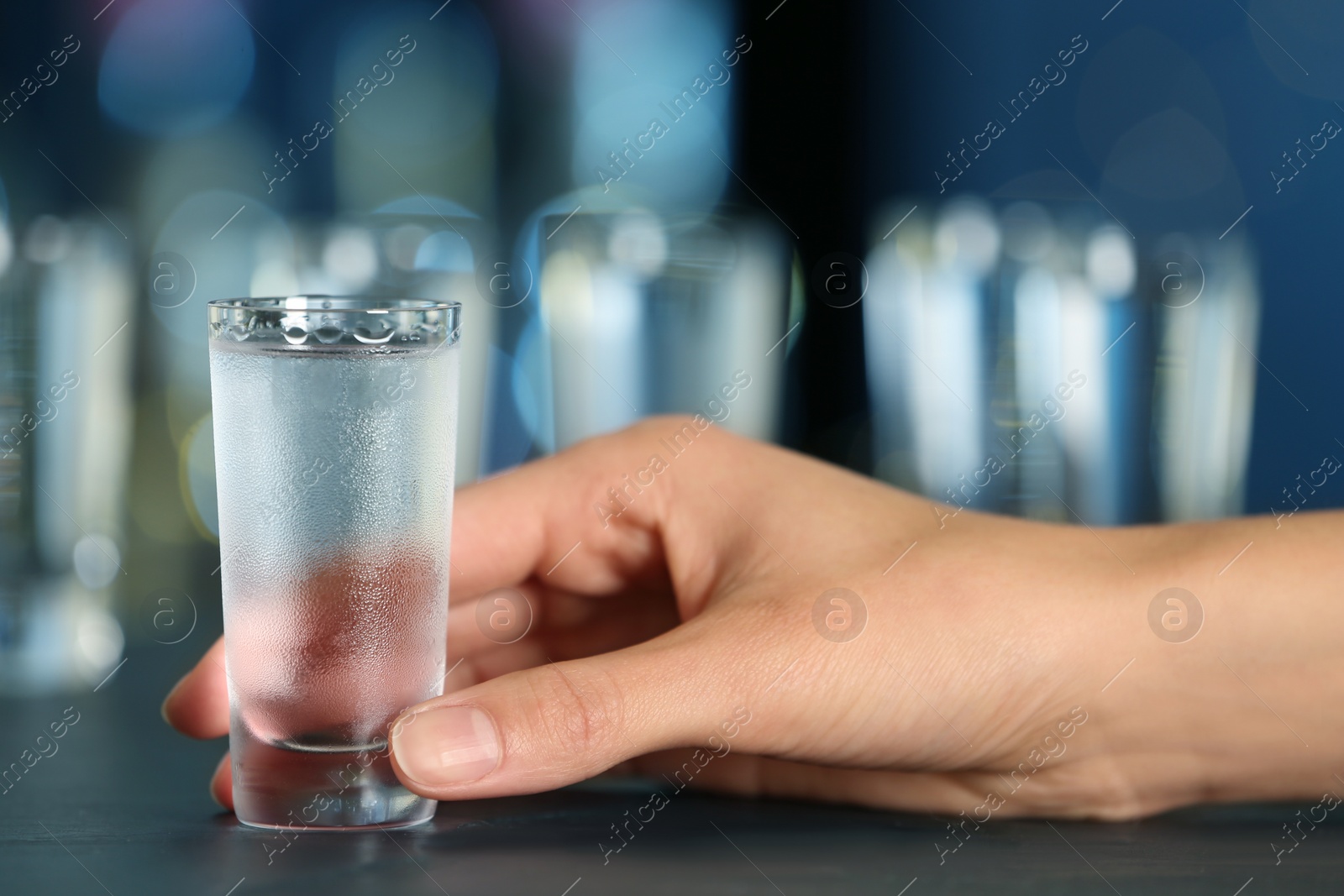 Photo of Woman with shot of vodka at table in bar, closeup