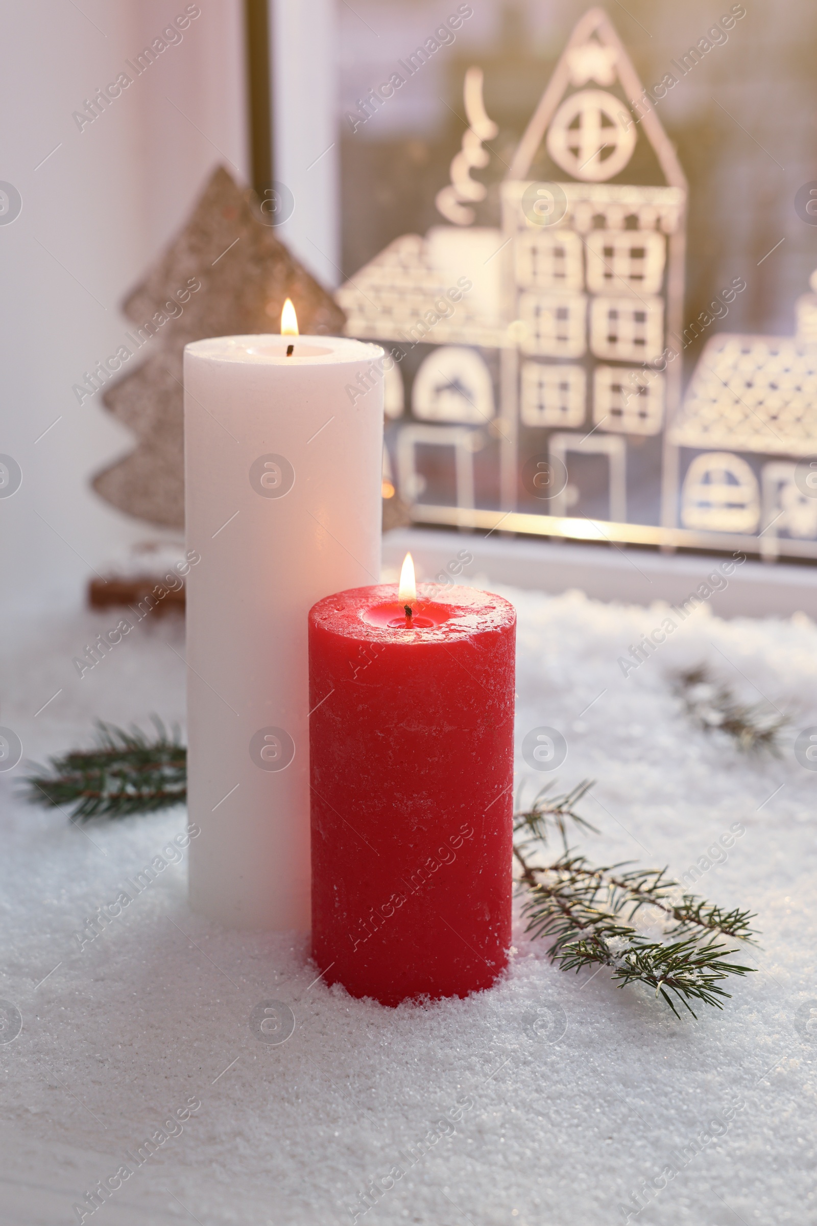 Photo of Beautiful burning candles with Christmas decor near window