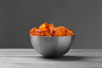 Photo of Bowl of sweet potato chips on table against grey background