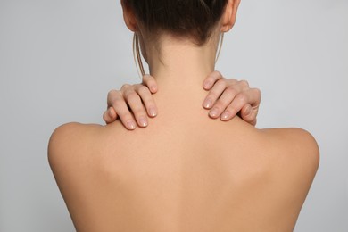 Photo of Back view of woman with perfect smooth skin on light background, closeup. Beauty and body care