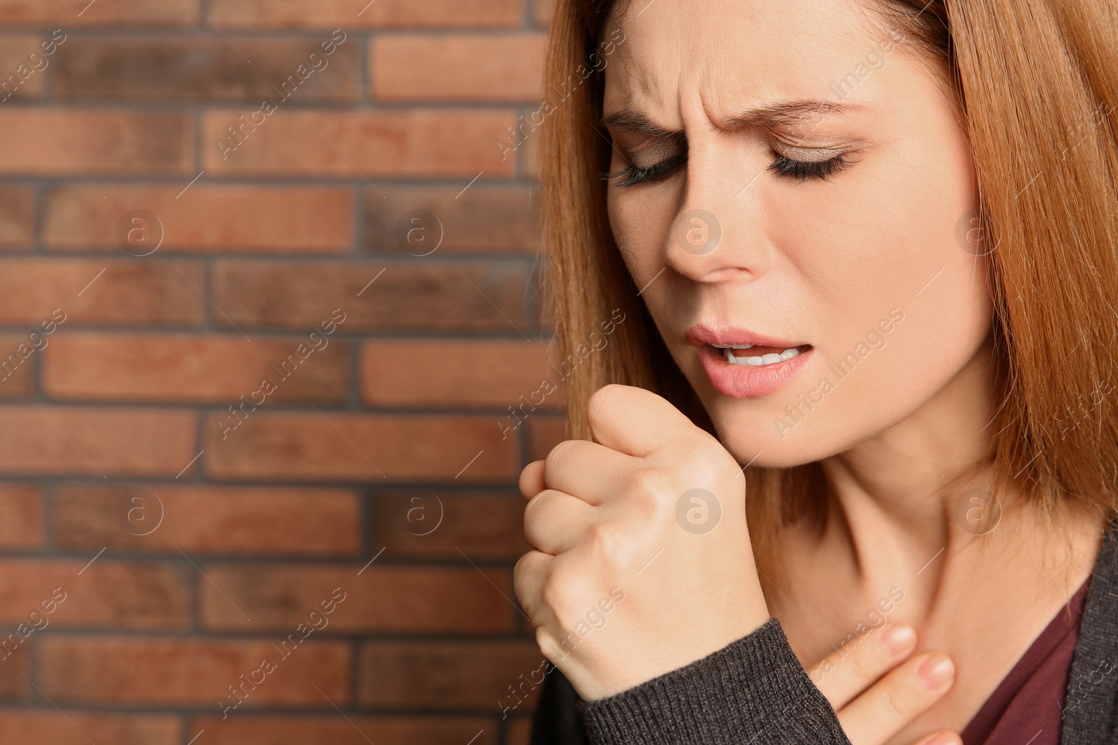 Photo of Woman suffering from cough near brick wall. Space for text