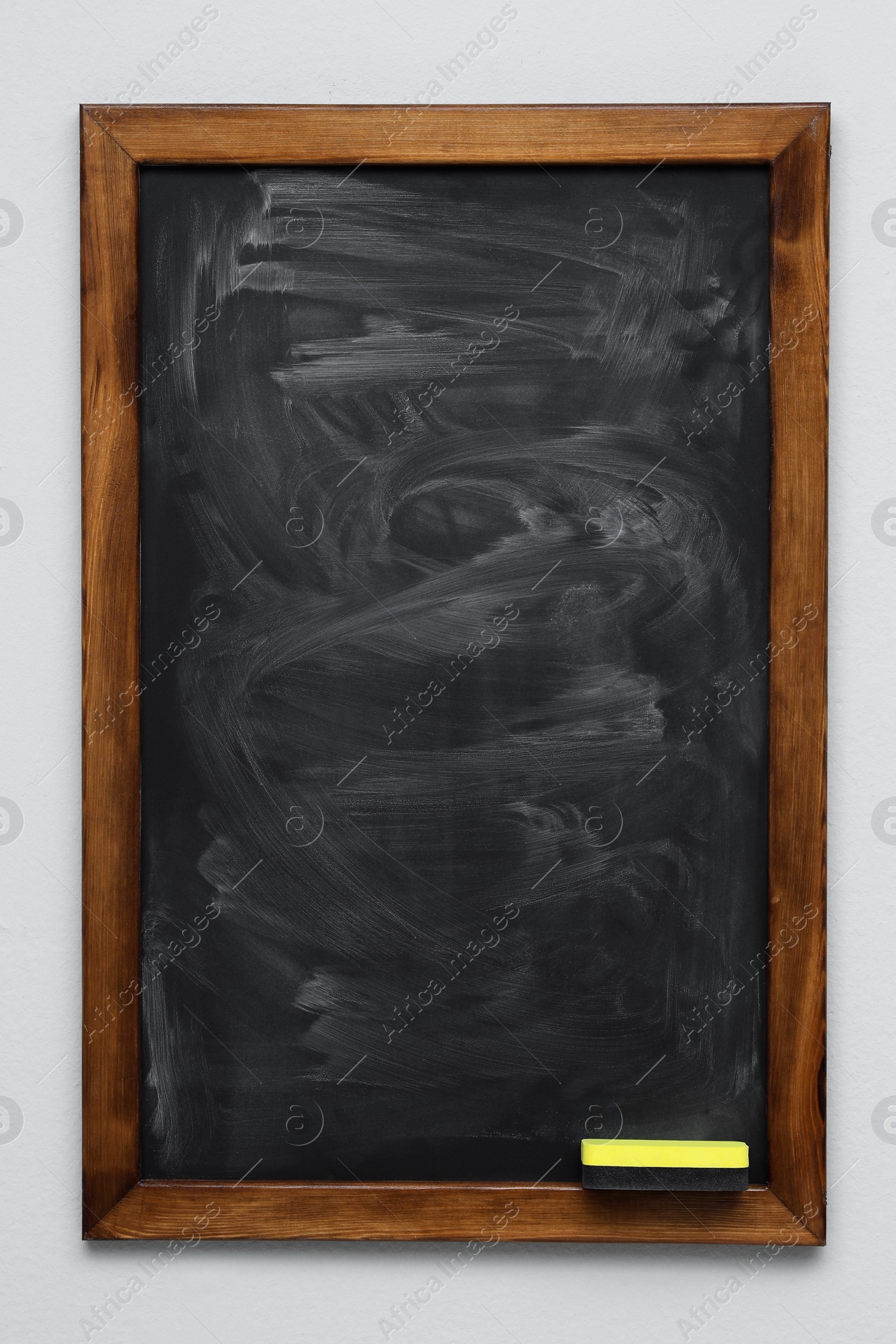 Photo of Dirty black chalkboard hanging on grey wall