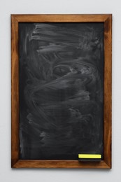 Dirty black chalkboard hanging on grey wall