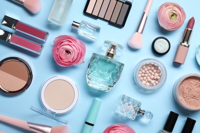 Flat lay composition with different makeup products and beautiful spring flowers on light blue background