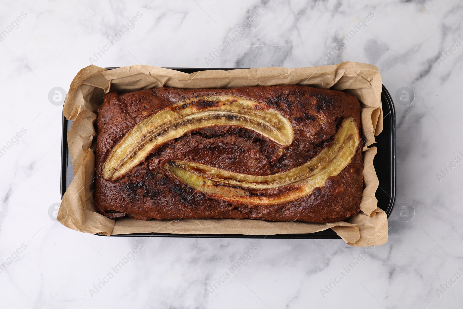 Photo of Delicious banana bread on white marble table, top view