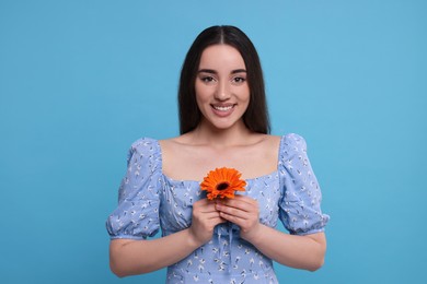 Beautiful woman with spring flower in hands on light blue background