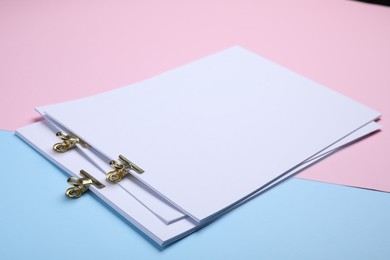 Sheets of paper with clips on color background