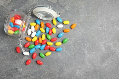 Photo of Overturned jar with jelly beans on stone background, top view. Space for text