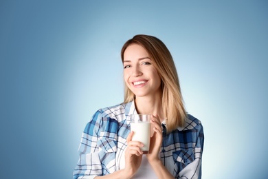 Beautiful young woman drinking milk on color background