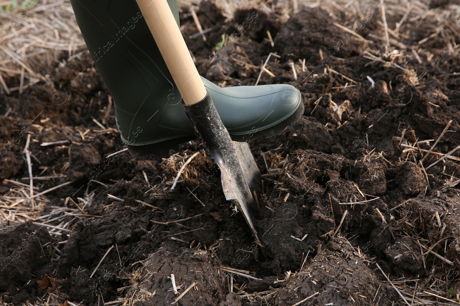 Photo of Worker digging soil with shovel outdoors, closeup